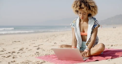 Girl working with laptop on beach